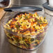 A Rubbermaid plastic container filled with multicolored spiral pasta.