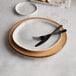 An American Metalcraft faux rustic wood melamine charger plate with a fork and knife on it.