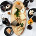 An American Metalcraft oval melamine serving board with a variety of foods on it.