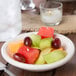 An Ivory china monkey dish filled with fruit on a table.