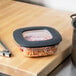 A Rubbermaid clear square storage container with pasta inside on a cutting board.