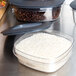 A clear Rubbermaid food storage container filled with white rice and coffee beans.