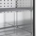 A metal shelf inside a True stainless steel reach-in freezer with a left-hinged door.