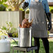 A woman using a Backyard Pro stainless steel stock pot to cook a turkey.