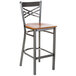 A Lancaster Table & Seating metal cross back bar stool with a wooden seat.