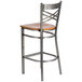 A Lancaster Table & Seating metal cross back bar stool with a cherry wood seat.