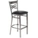 A Lancaster Table & Seating clear coat finish cross back bar stool with a black cushion.