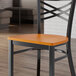 A Lancaster Table & Seating cherry wood seat on a black metal chair.