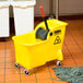 A yellow Rubbermaid mop bucket with a black handle and a red reverse press wringer.