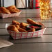 A red check paper food tray filled with fried chicken and sauce.