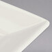 A close-up of a Homer Laughlin Ivory square china plate with a curved edge.