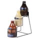 A Ghirardelli 3-tier sauce rack holding bottles of liquid on a counter.