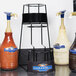 A Ghirardelli 3-tier flavoring sauce rack holding bottles of chocolate syrup.