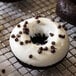 A donut with Ghirardelli white chocolate coating and chocolate chips on a cooling rack.