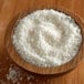 A bowl of Regal shredded coconut on a wooden table.