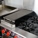 An FMP add-on charbroiler on a metal griddle over a stove.