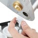 A person using a plastic tool to remove a metal cylinder.