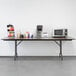 A Correll walnut folding table with a brown surface holding coffee and a coffee machine.