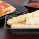 A rectangular black deli server holding a variety of food on a table.