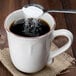 A spoonful of sugar being poured into a 10 Strawberry Street Oxford brown rim stoneware mug filled with coffee.