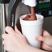 A person pouring a Carnival King root beer slushy into a cup.