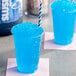 A blue liquid in a plastic cup with a blue and white striped straw.