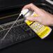 A hand using Noble Chemical Dust-B-Gone to spray a keyboard.