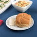 An Arcoroc white porcelain bread and butter plate with bread on it.