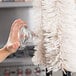 A person using a Bar Maid glass washer to clean a glass cup.