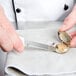 A person using a Mercer Culinary clam knife to open a clam shell.