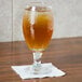 A glass of beer on a table with a white Choice beverage napkin.