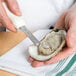 A person holding a Mercer New Haven style oyster knife and an oyster.