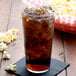 A Cambro clear plastic tumbler with soda and ice in it.