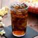 A Cambro clear plastic tumbler of ice tea with ice and popcorn.