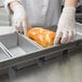 A person in gloves holding a loaf of bread in a Chicago Metallic bread loaf pan.