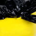 A black plastic bag on a yellow Continental Huskee trash can.