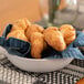 A round white stoneware bowl filled with croissants on a table.