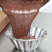 A person pouring batter into a Chicago Metallic Lava Cake Pan.