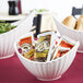 A white porcelain boat bowl with line texture filled with bread on a hotel buffet counter.