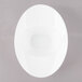 A white oval porcelain bowl with a rim on a gray surface.