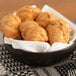 A round black stoneware serving bowl filled with croissants on a table.