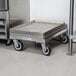 A Channel bun pan dolly with a stack of metal trays on wheels.