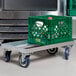 A green milk crate on a metal dolly.