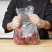 A person in a chef's uniform holding a plastic bag of food.