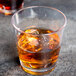 A close up of two GET Loft double rocks glasses filled with amber liquid and ice.