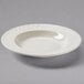 A white Tuxton pasta bowl with a swirl design on the rim.