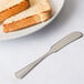 A silver Libbey butter spreader next to a piece of toast.