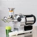 A Hamilton Beach wheatgrass juicer next to a glass of green liquid.
