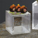 Two American Metalcraft clear square acrylic risers with sushi rolls on top.