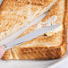 A Libbey stainless steel bread and butter knife spreading butter on a piece of toast.